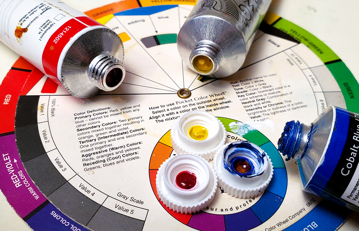 Closeup of a color wheel with open primary color paint tubes on it.